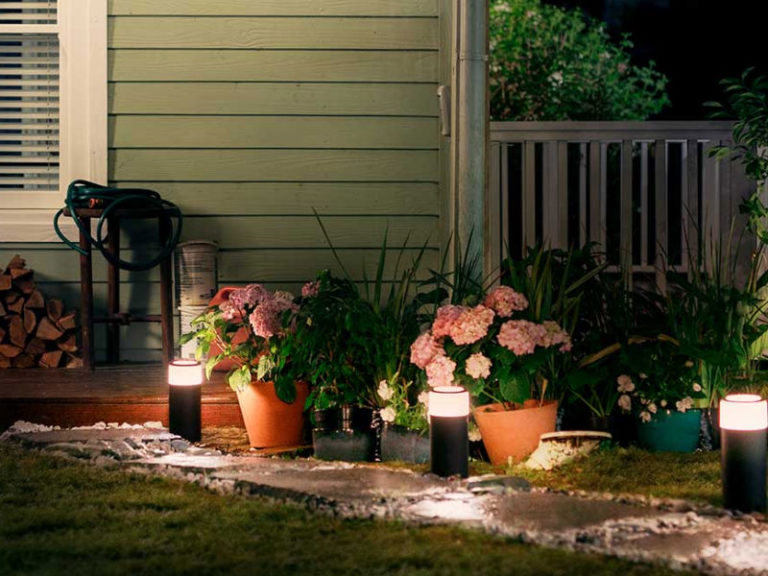 Tuin met netjes gemaaid gras, tuinlampen en bloemen